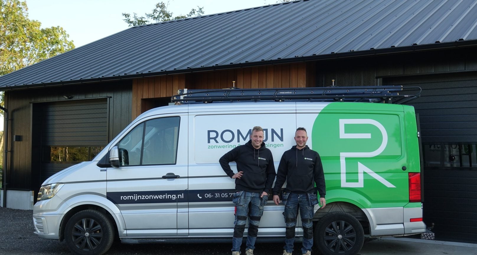André en Gerben Romijn naast de bedrijfsbus met het groene logo, voor het donkere bedrijfspand